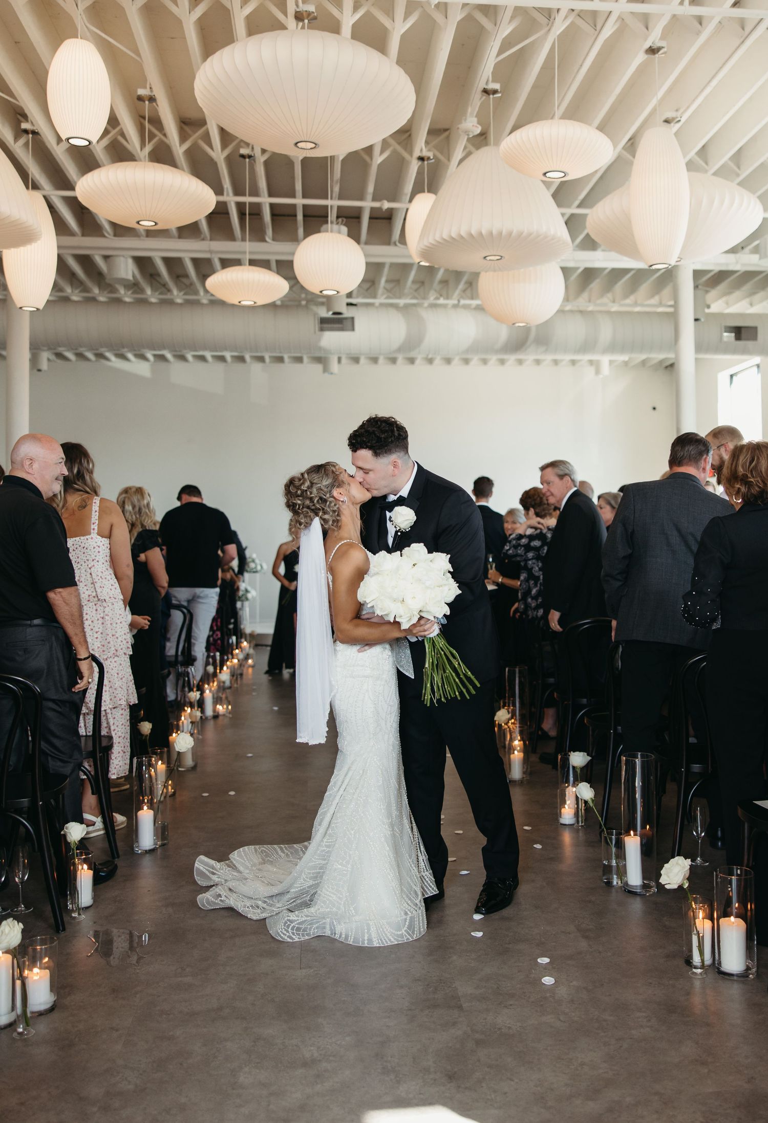 Wedding reception venue with paper lanterns and guests mingling in formal attire.