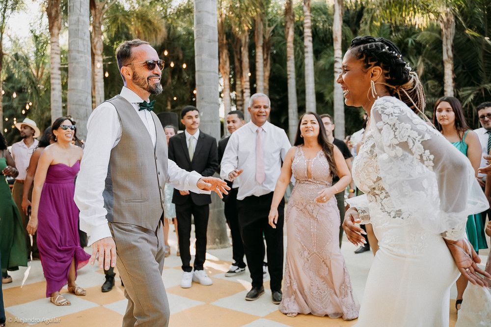 Bride and groom share a joyful first dance at an outdoor wedding reception surrounded by smiling guests.