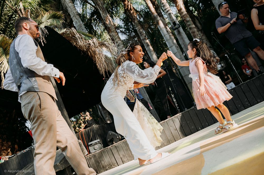 Bride dancing joyfully with a young girl in a pink dress at an outdoor wedding reception.