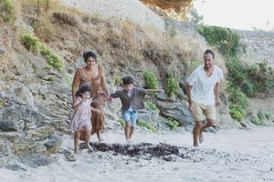 Parents et enfants courant sur la plage pendant une séance photo famille