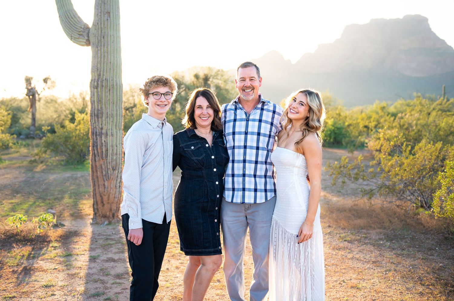 Family of four on vacation in Arizona stating in the desert at Phon D Sutton at golden hour during their family vacation photo session.