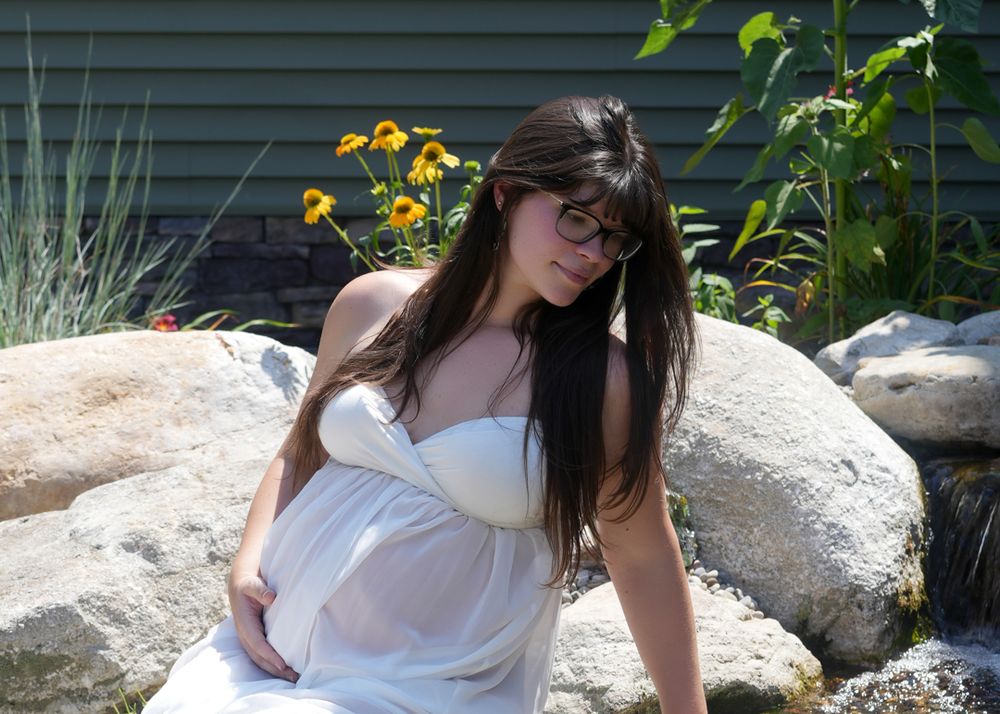 Five artistic maternity photos captured outdoors against a backdrop of rocks and garden flowers.