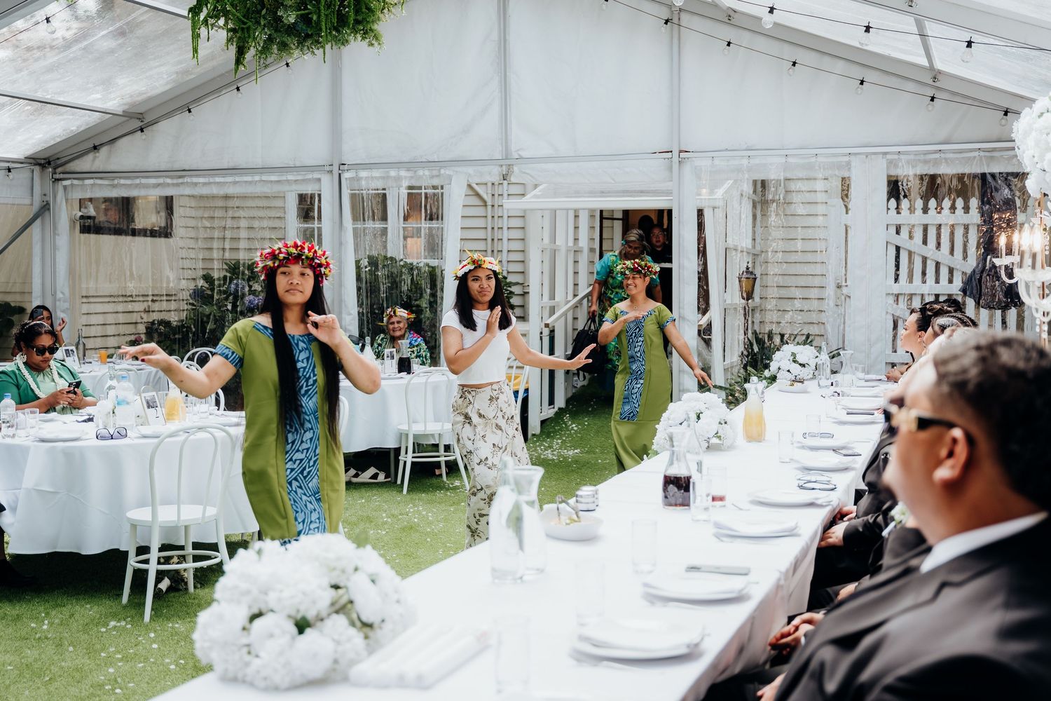 White chairs and a decorative arch are arranged for an outdoor wedding ceremony in a lush garden setting.