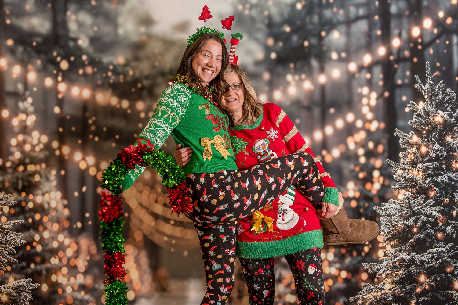 A crying baby in Christmas pajamas sits on Santa Claus's lap in front of a festive Santa's Workshop backdrop.