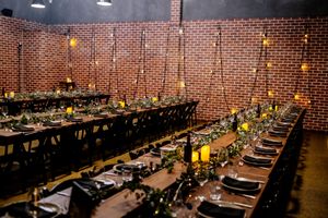 Elegant banquet hall with long wooden tables, greenery, candles, and brick walls for a rustic wedding reception at Factory 51 Brisbane