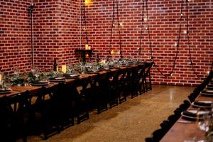 Elegant private dining room with long black table, dark chairs, brick walls, and candlelit greenery centerpieces Factory 51 Brisbane