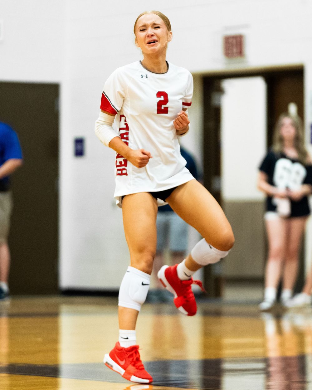 Female volleyball player wearing number 2 jersey runs on indoor court during a competitive match.