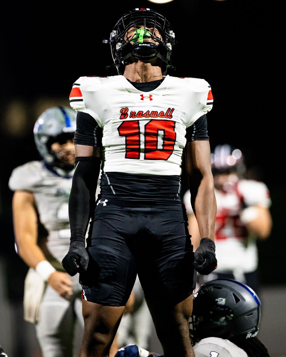 Braswell high school football player number 10 stands triumphantly during a night game.