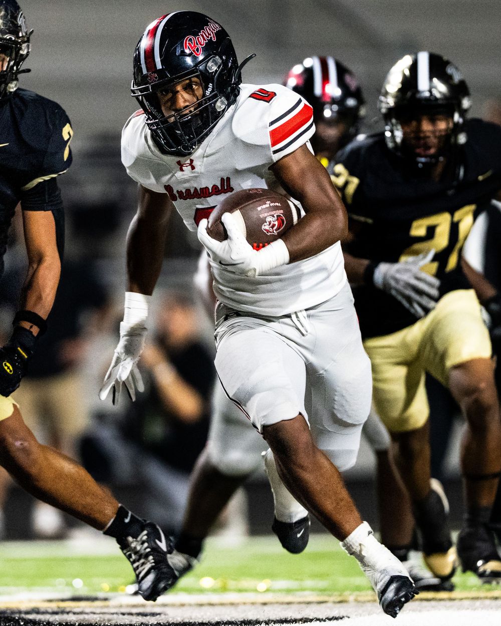 Braswell football player number 1 runs with the ball during a high school night game.