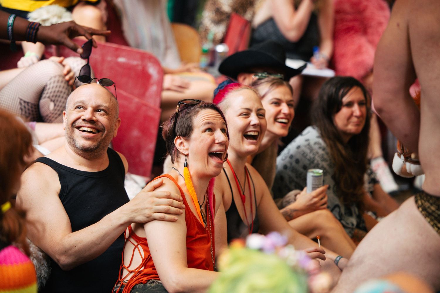 Crowd of joyful festival-goers laughing and celebrating together at a colorful outdoor music event.