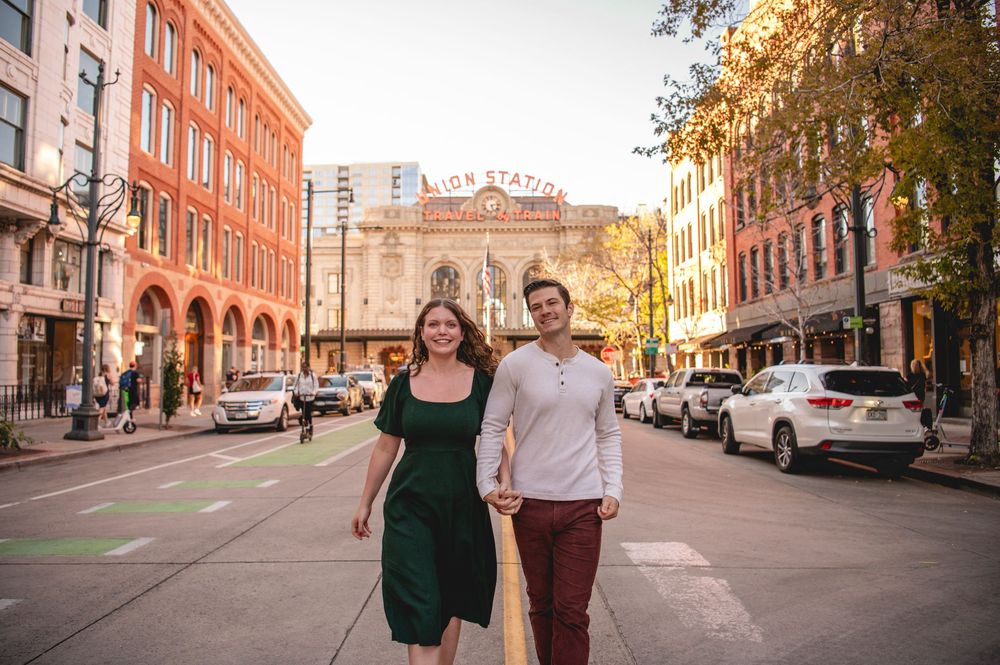 Couple smiling and holding hands on a city street near Union Station on a sunny fall day.