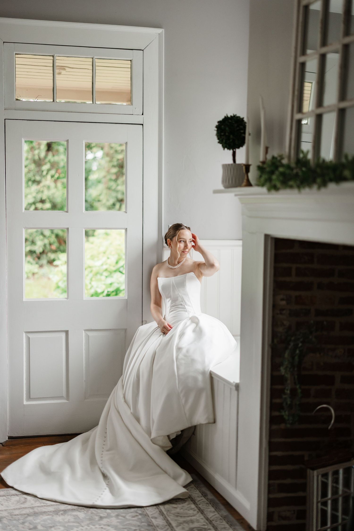 Bride in a strapless white ball gown with train poses by a white door and fireplace in an elegant interior.
