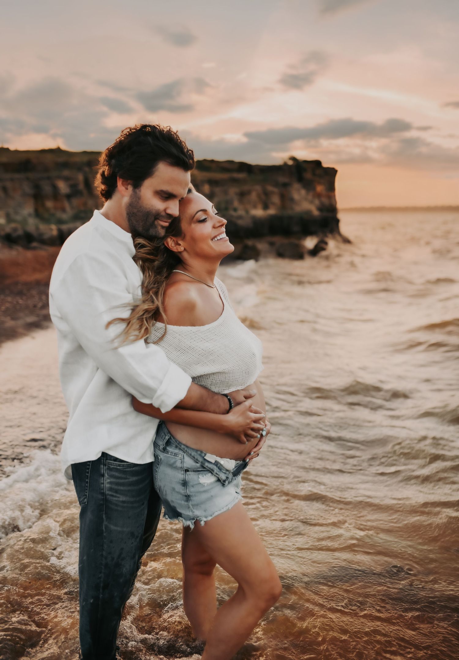 Couple smiling during sunset maternity portraits