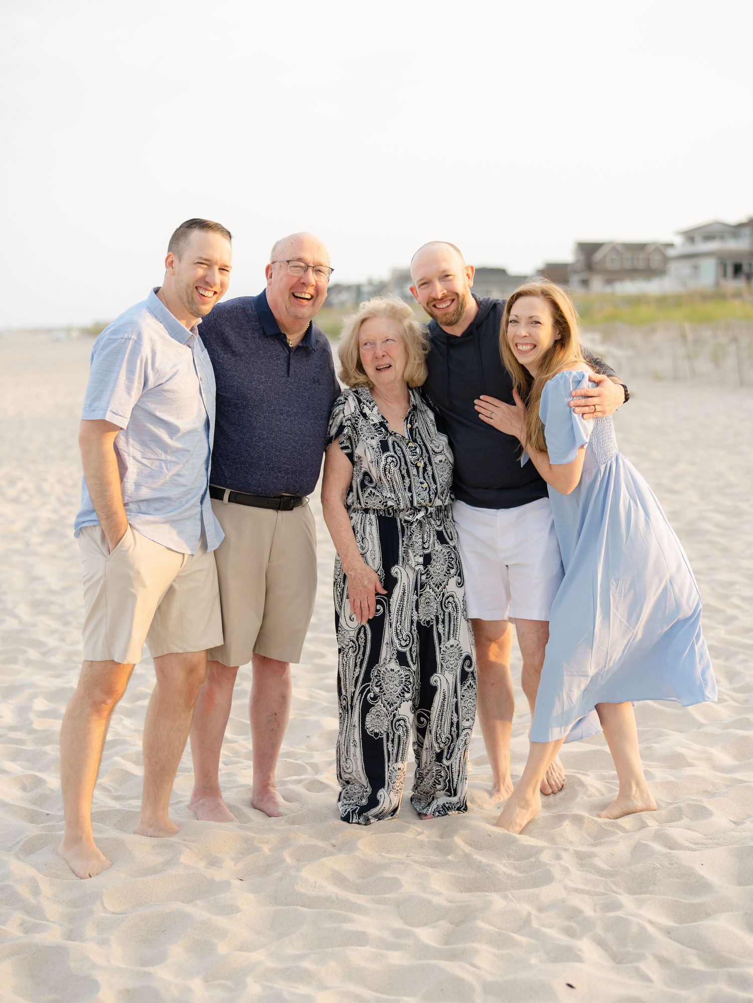 Extended family siblings smiling together on the sand during a golden hour portrait session at Mantoloking Beach, NJ.