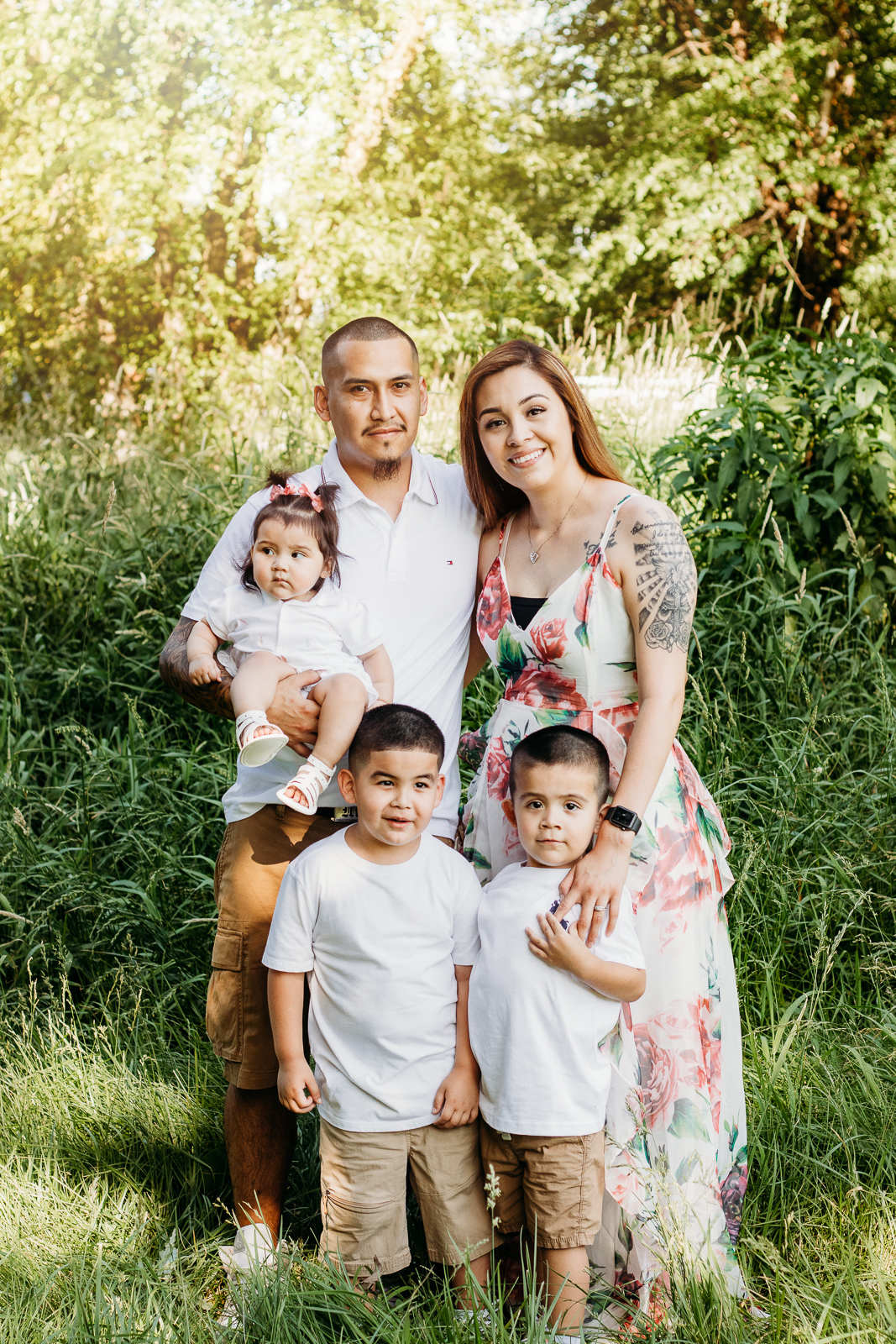 A family of 5 standing and smiling together for a photo.