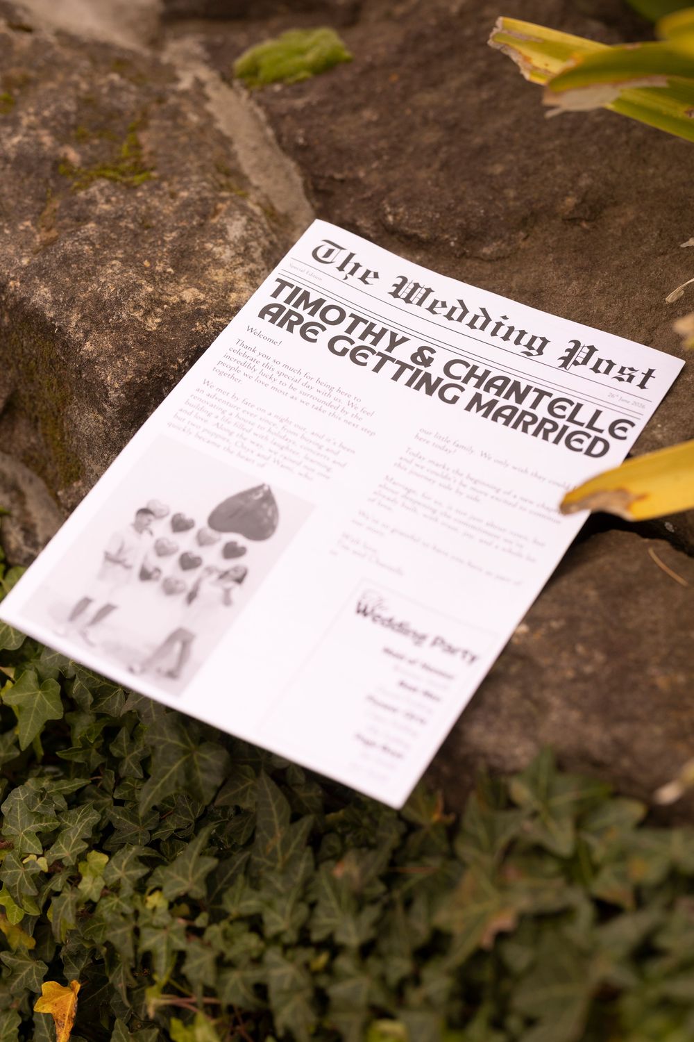 Wedding newspaper program for Timothy and Chantelle's marriage announcement, displayed on rustic stone steps surrounded by ivy.