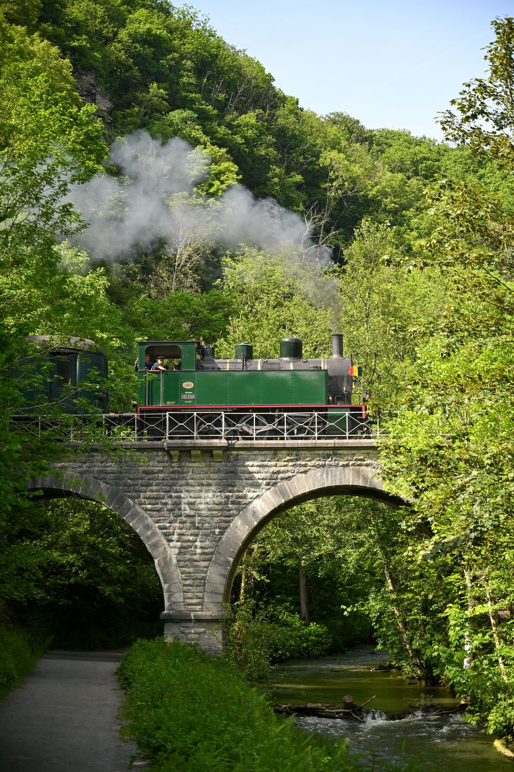 Même train vintage sur un viaduc, verdure environnante