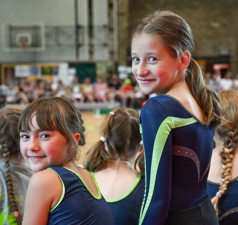 Deux fillettes en justaucorps, pendant un spectacle de fin d'année dans une école de gym, l'une se retournant vers l'objectif