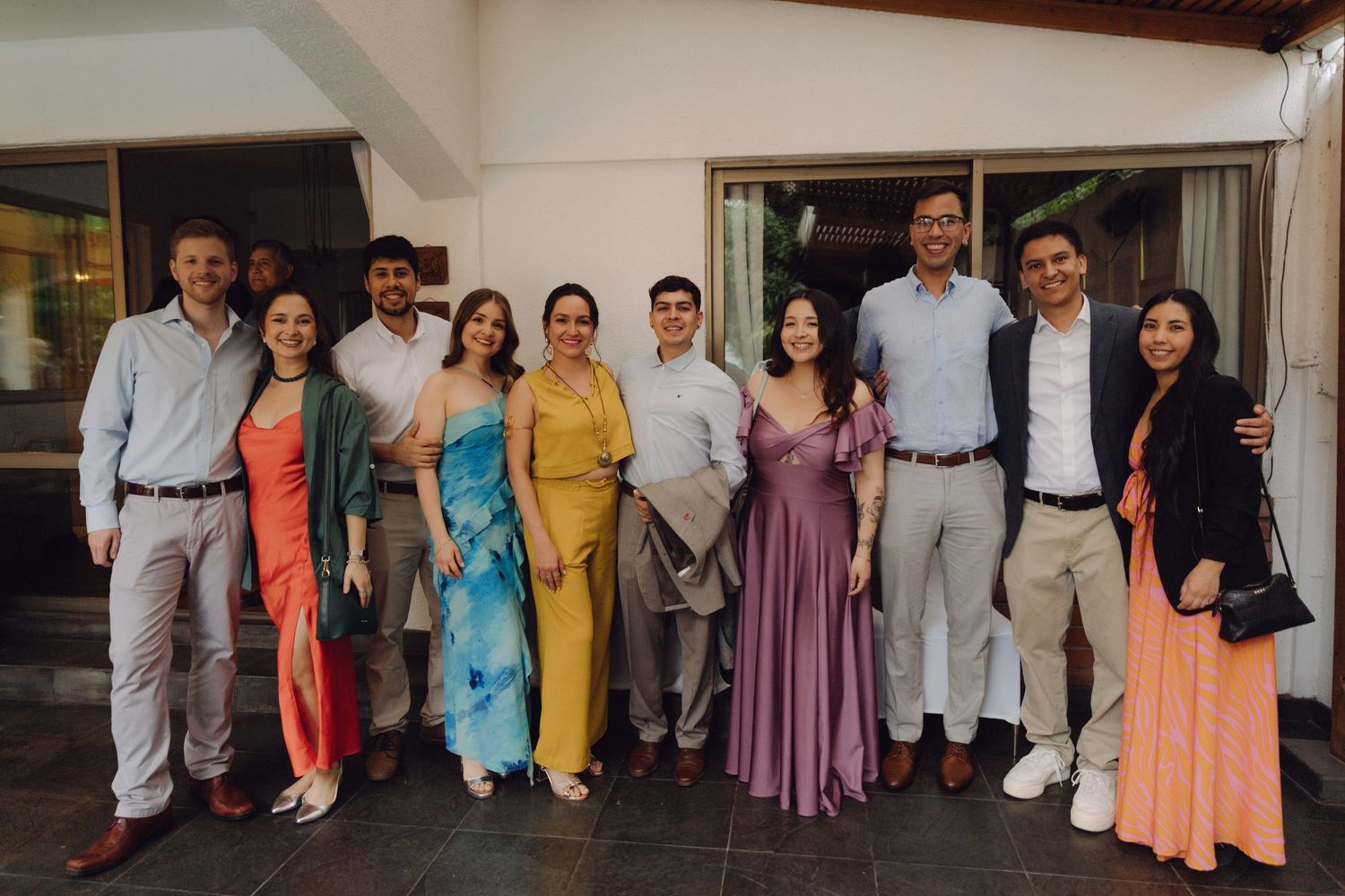Large group of elegantly dressed wedding guests posing together for a photo at an outdoor reception.