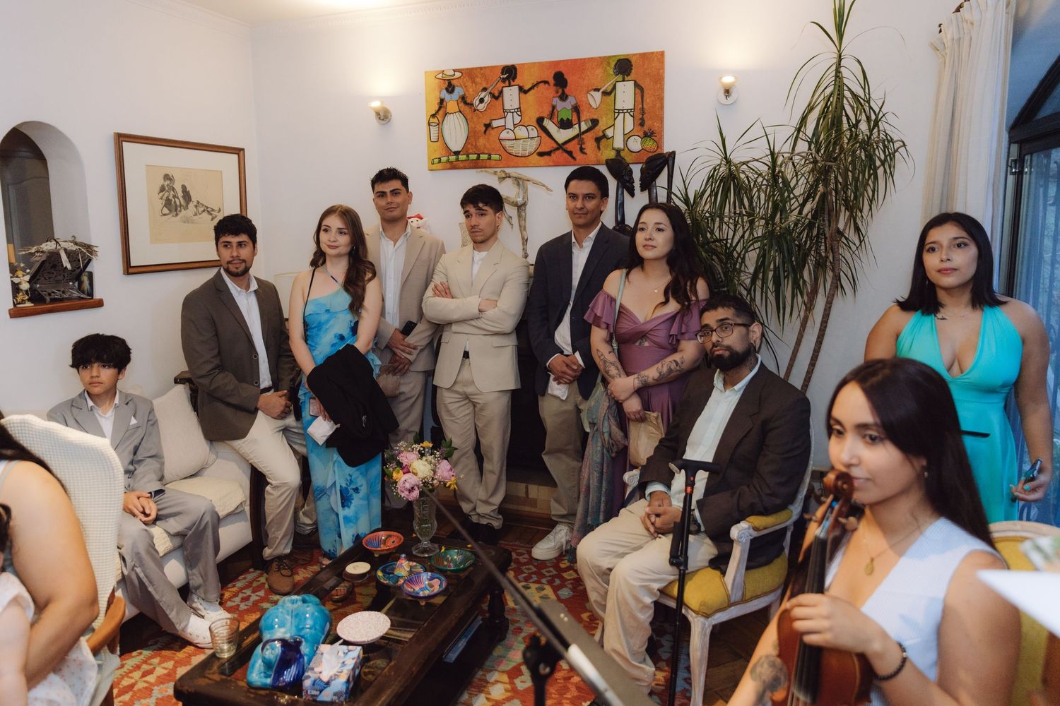 A group of elegantly dressed guests pose together in a decorated living room during an intimate wedding celebration.