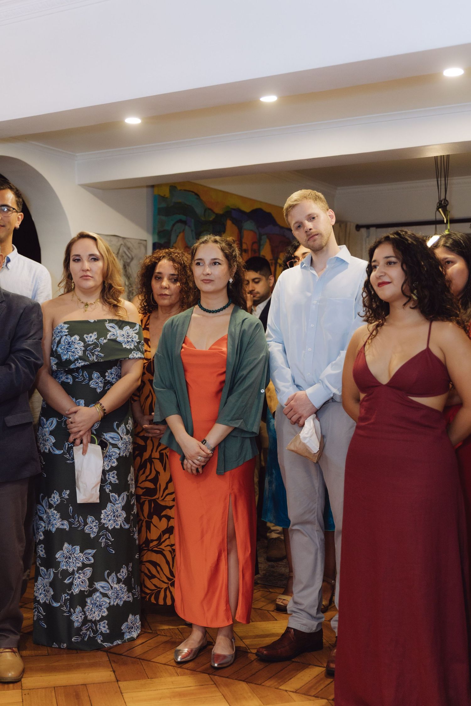 Wedding guests in formal attire standing and watching ceremony in elegantly decorated indoor venue.