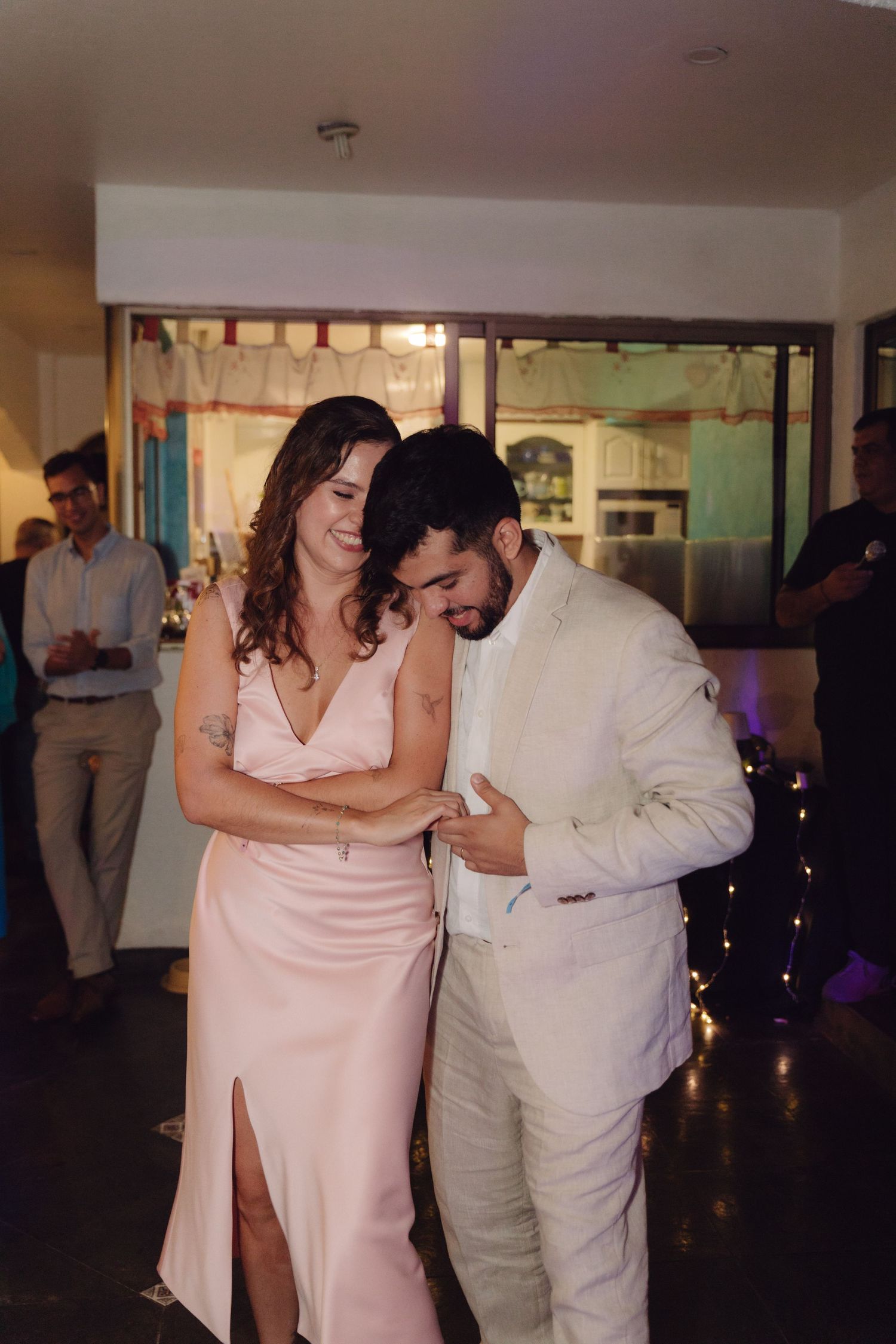 Couple in wedding attire laugh together while sharing an intimate dance at their reception.
