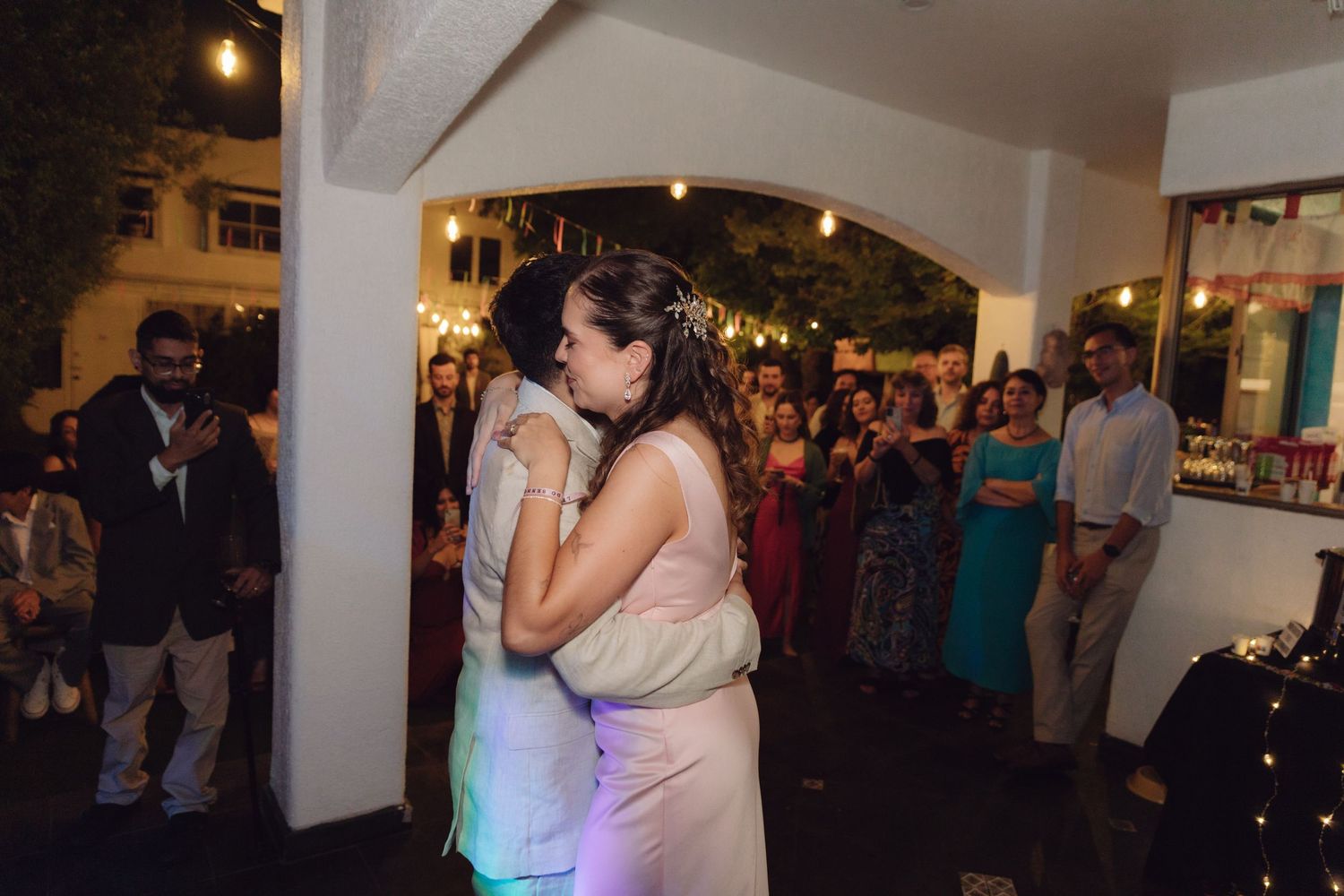 Couple shares a close embrace on outdoor dance floor surrounded by wedding reception guests.