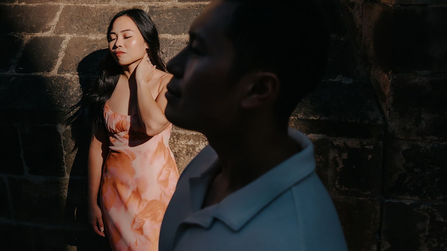 An elegant engagement portrait of a couple embracing warmly beneath a medieval stone archway in Barcelona's Old City.