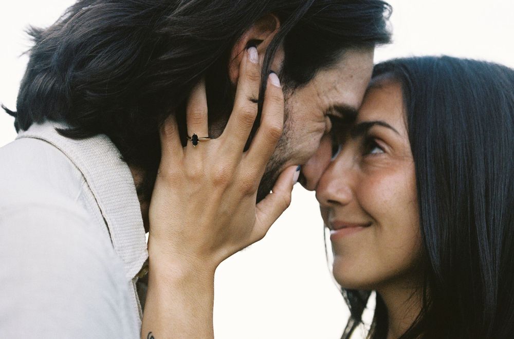 A romantic couple sharing an intimate moment, touching foreheads and smiling tenderly at each other.