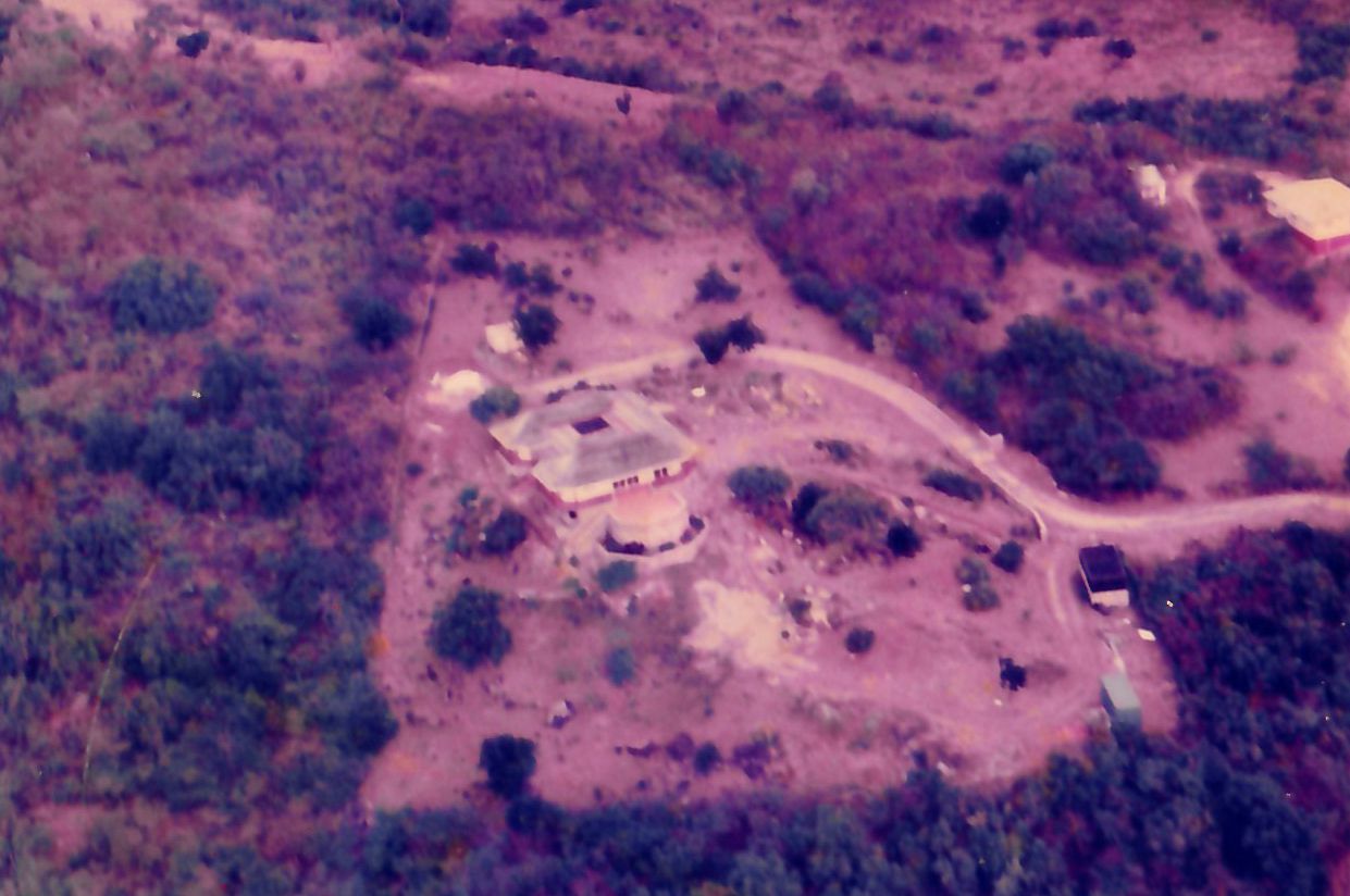 Aerial view of a remote military outpost surrounded by dense jungle vegetation on cleared terrain.