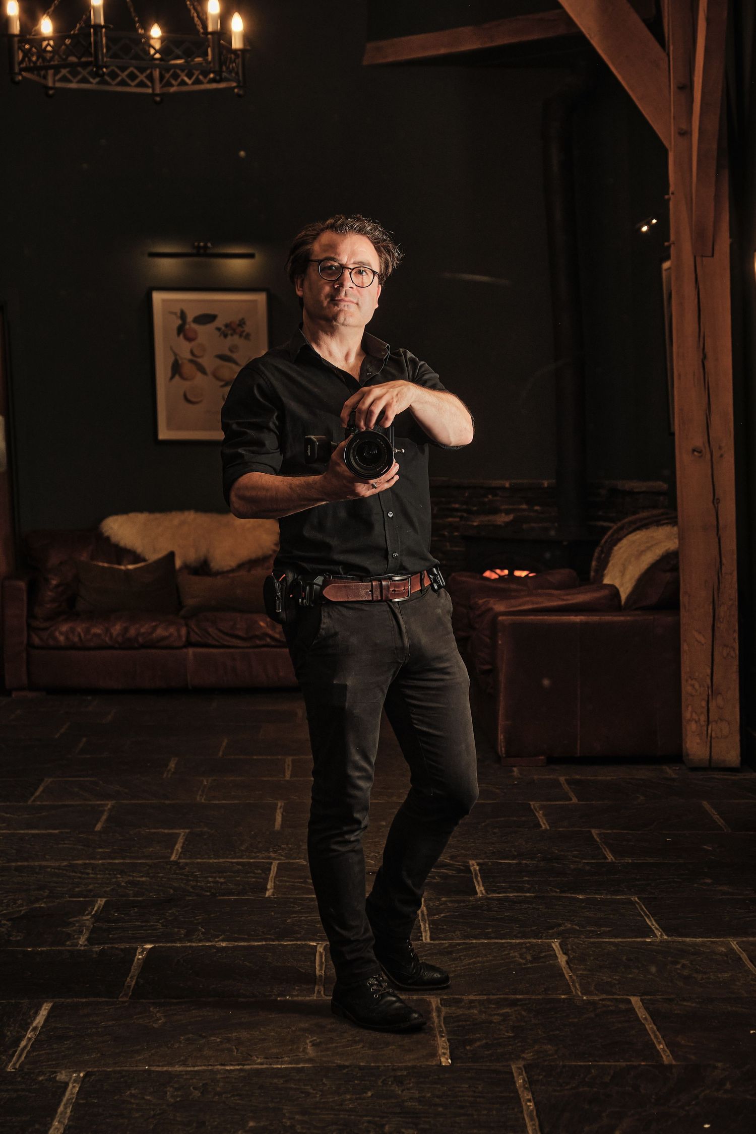 Four moody photos show a photographer wearing dark clothing while taking photos in a dimly lit room with candles.