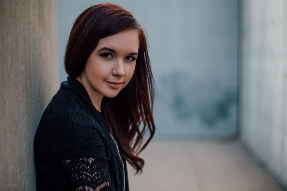 headshot of white red headed woman, with long hair in a sculpture garden