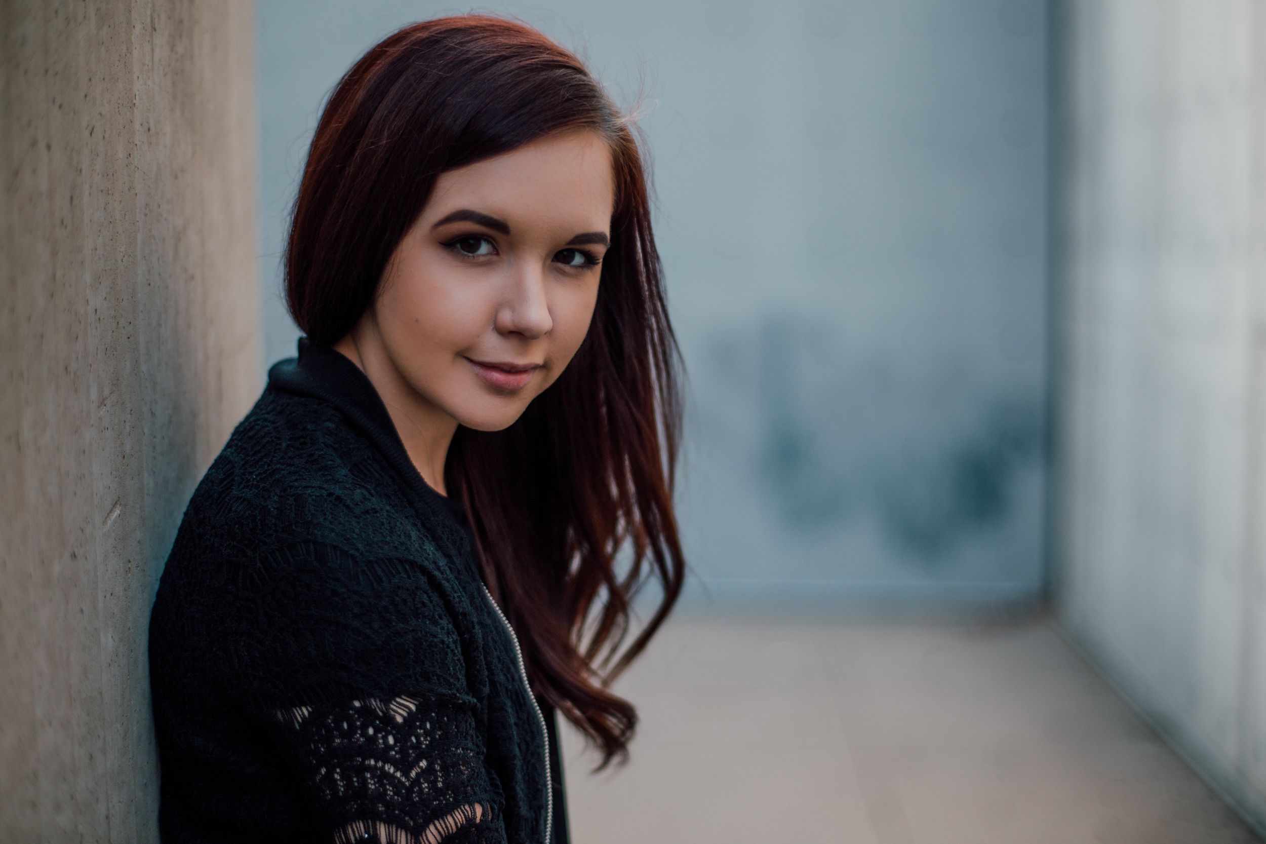 headshot of white red headed woman, with long hair in a sculpture garden