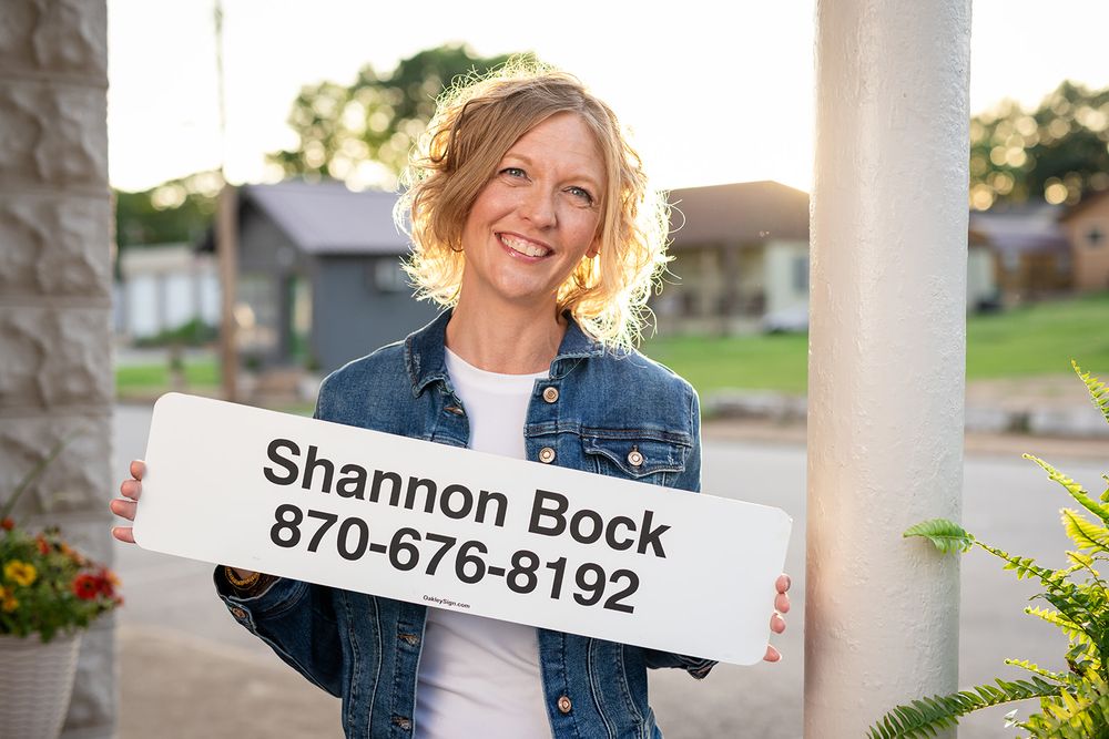 Realtor holding her real estate name sign for a personal branding session in downtown Cotter, Arkansas