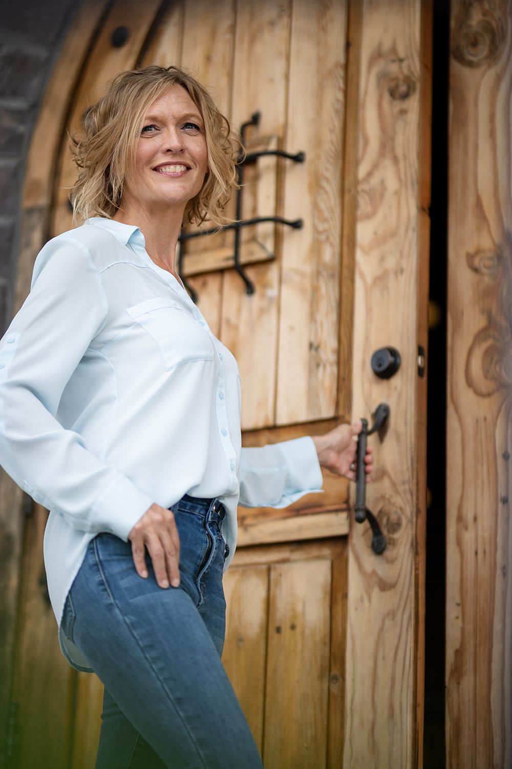 Real estate agent leaning against a rustic wooden door during a personal branding photo in Gassville, Arkansas