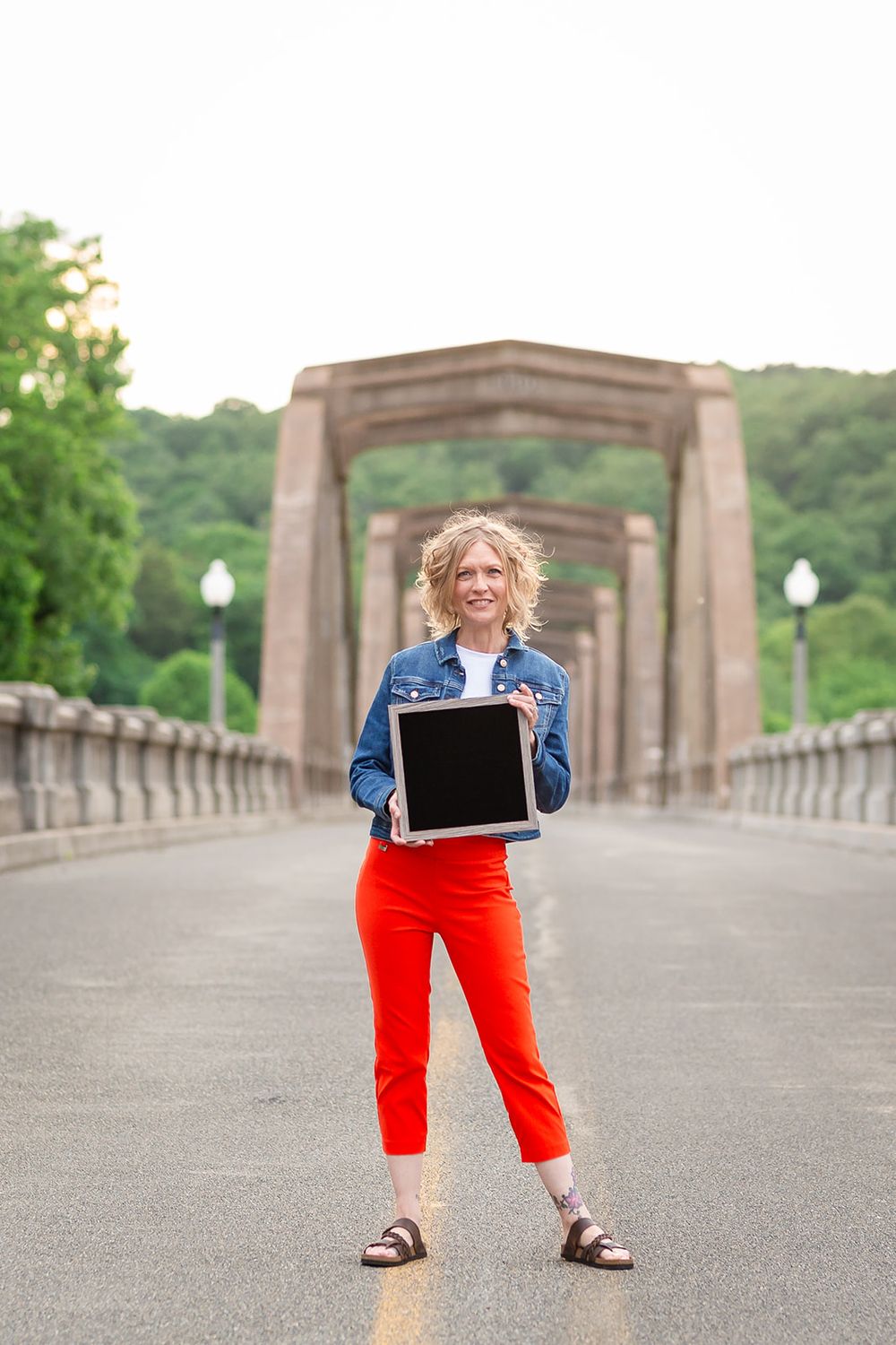 Real estate agent holding a tablet on the Cotter Bridge during a personal branding session in Cotter, Arkansas