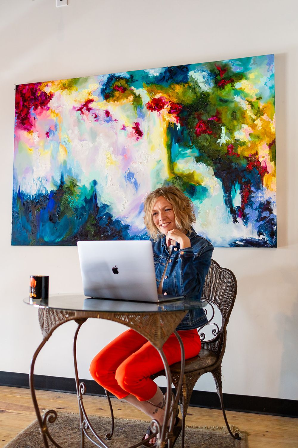 Realtor working on a laptop below a colorful painting during a coffee shop personal branding session in Gassville, Arkansas