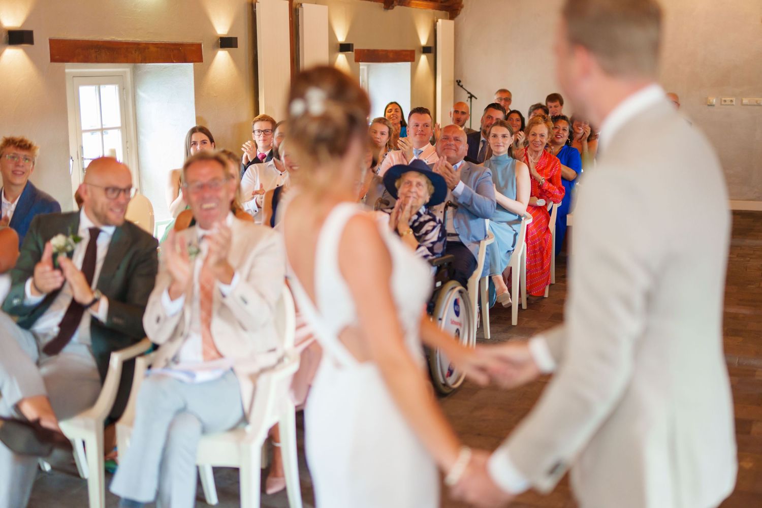 Indoor wedding ceremony with guests seated in rows watching celebration.