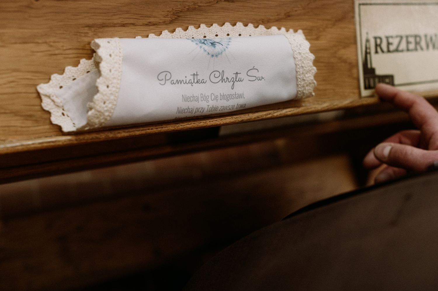 Close-up of a decorative white lace label with handwritten text on a wooden surface near a reserved sign.