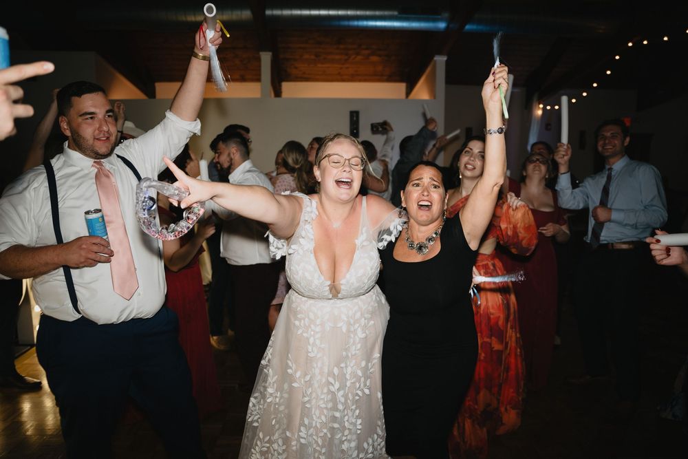 Bride and guests dancing joyfully at a wedding reception, arms raised in celebration.