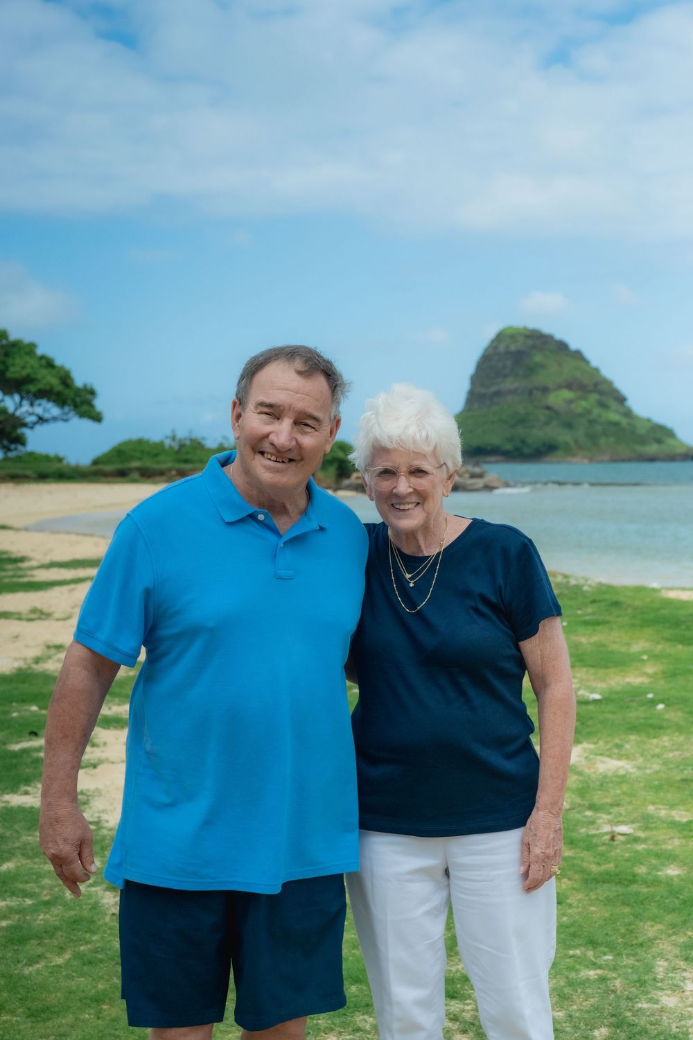 A mom and dad posing in front of mokolii island.