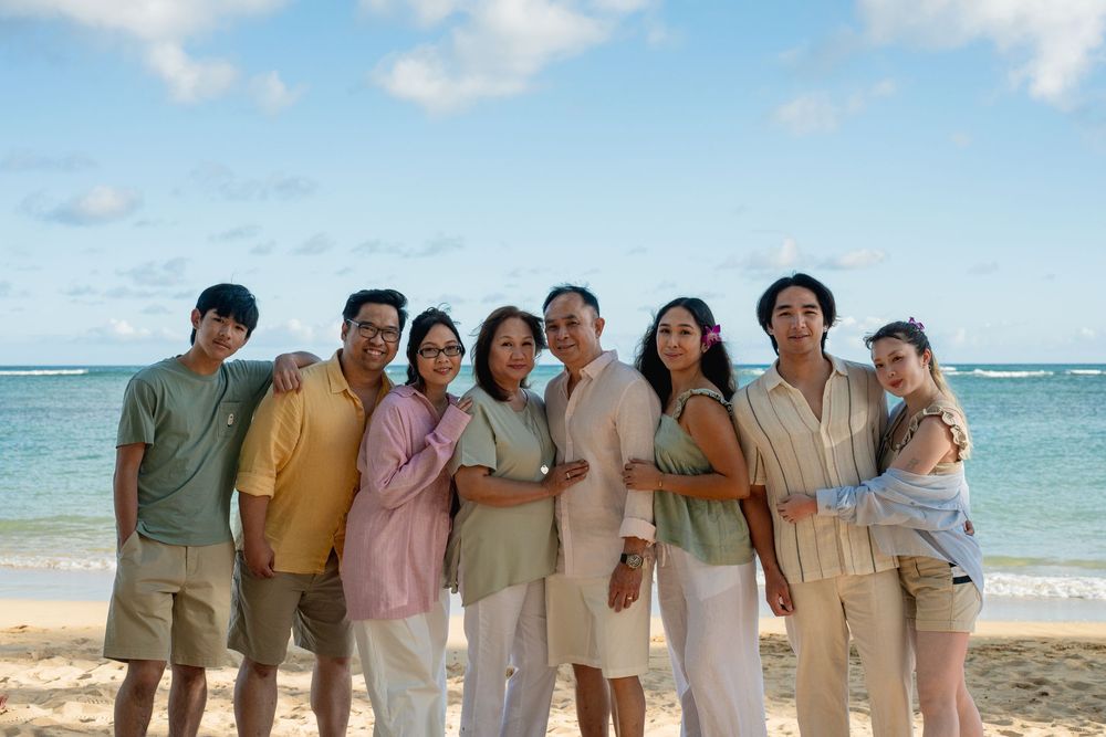 Family photograph at the beach, with all members of the family wearing pastel colors.