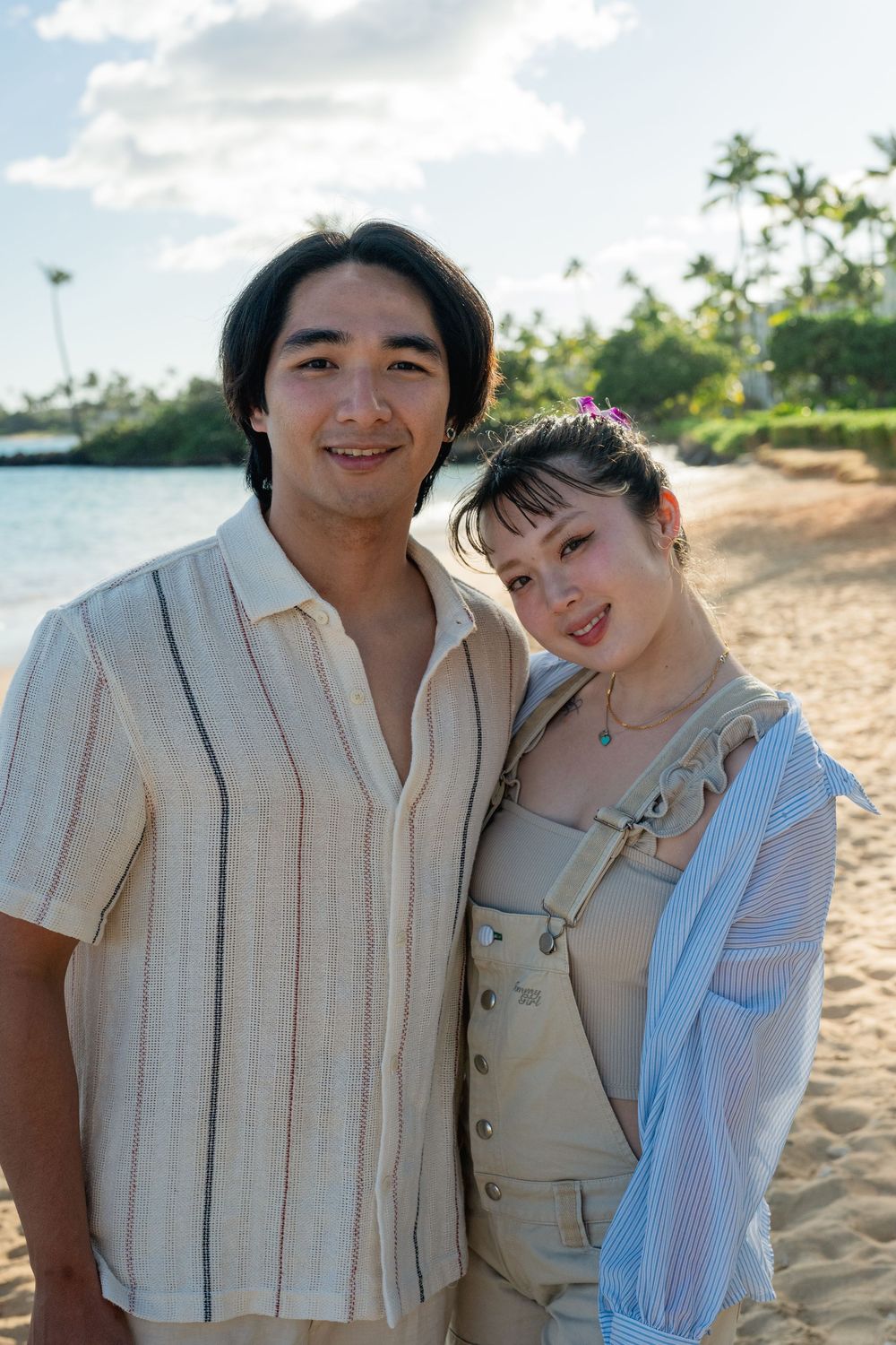 A couple on the beach, smiling at sunset.
