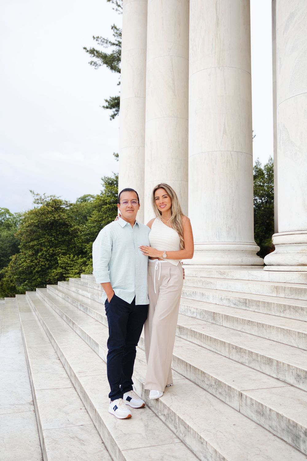 Couple posing on marble steps beside tall white columns at the Jefferson Memorial in Washington, D.C.