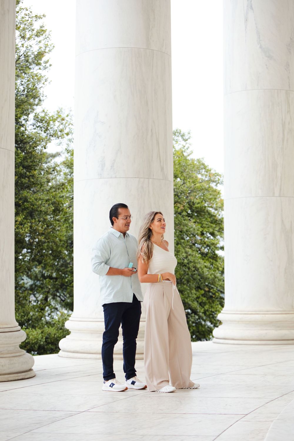 Couple posing between white marble columns at the Jefferson Memorial in Washington D.C.