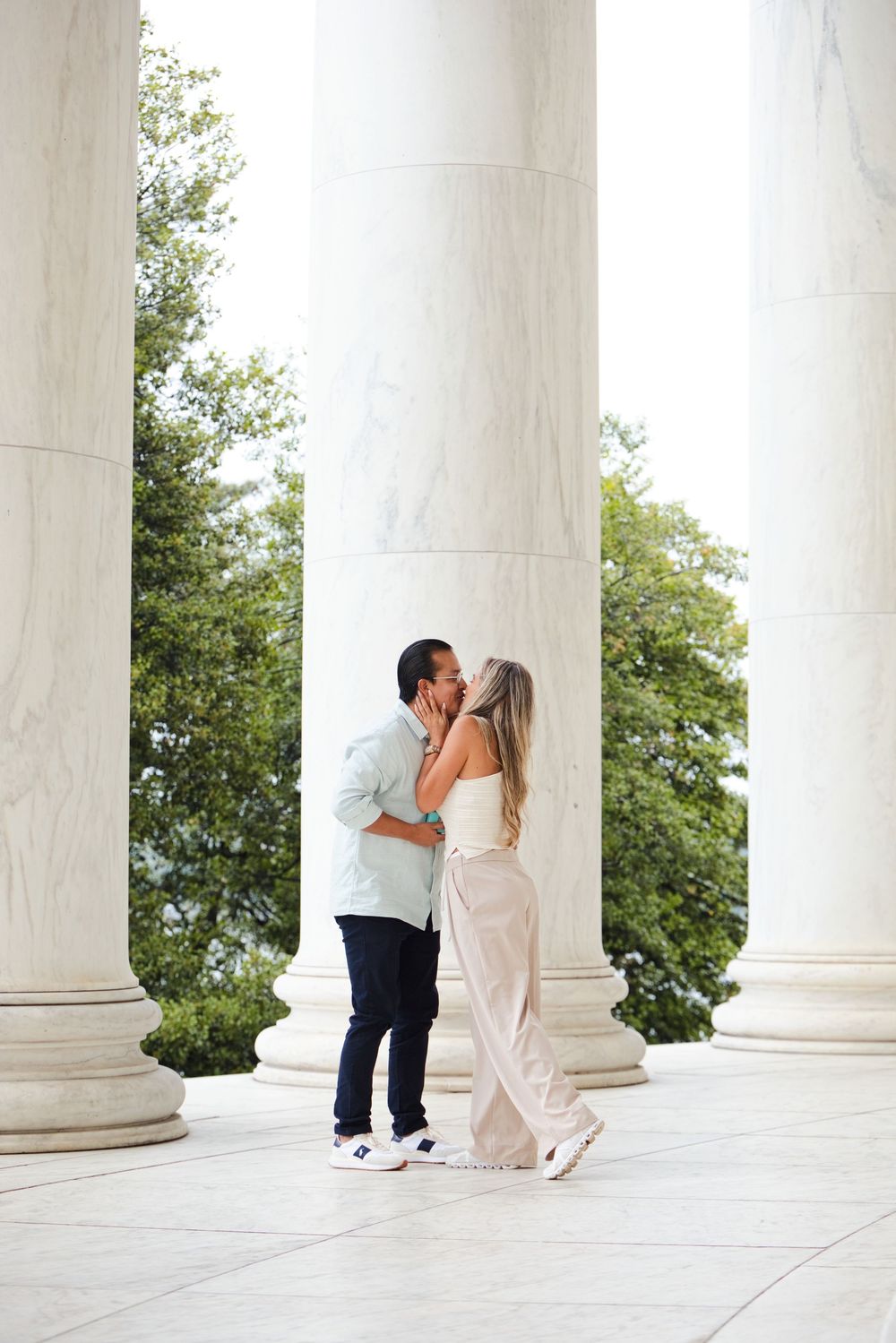 Couple sharing a romantic kiss between marble columns at the Jefferson Memorial in Washington D.C.