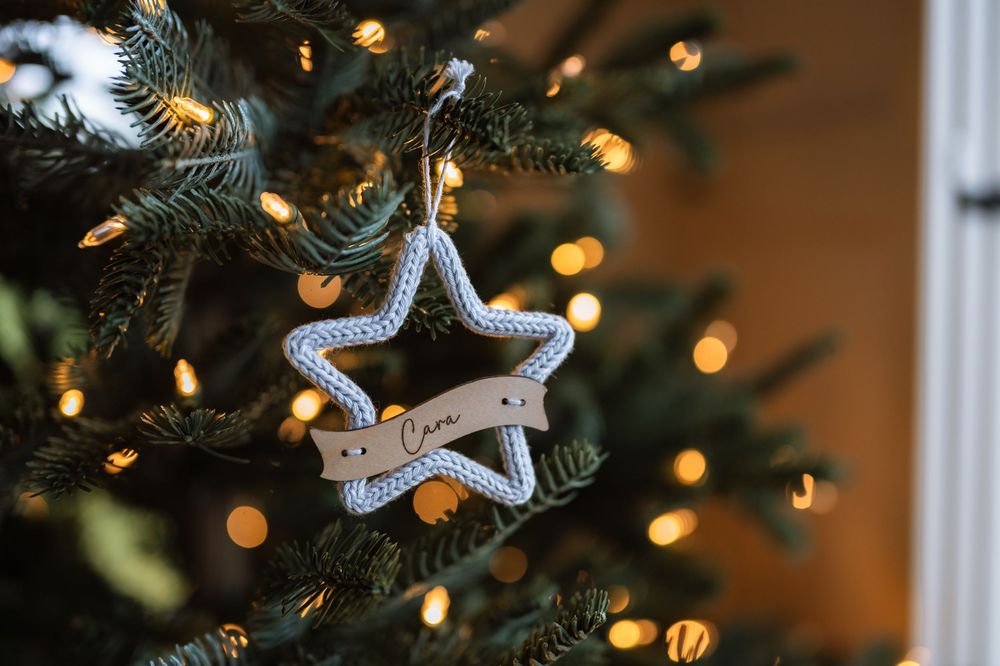 Christmas tree branches with twinkling bokeh lights and silver star ornaments create a festive holiday scene.