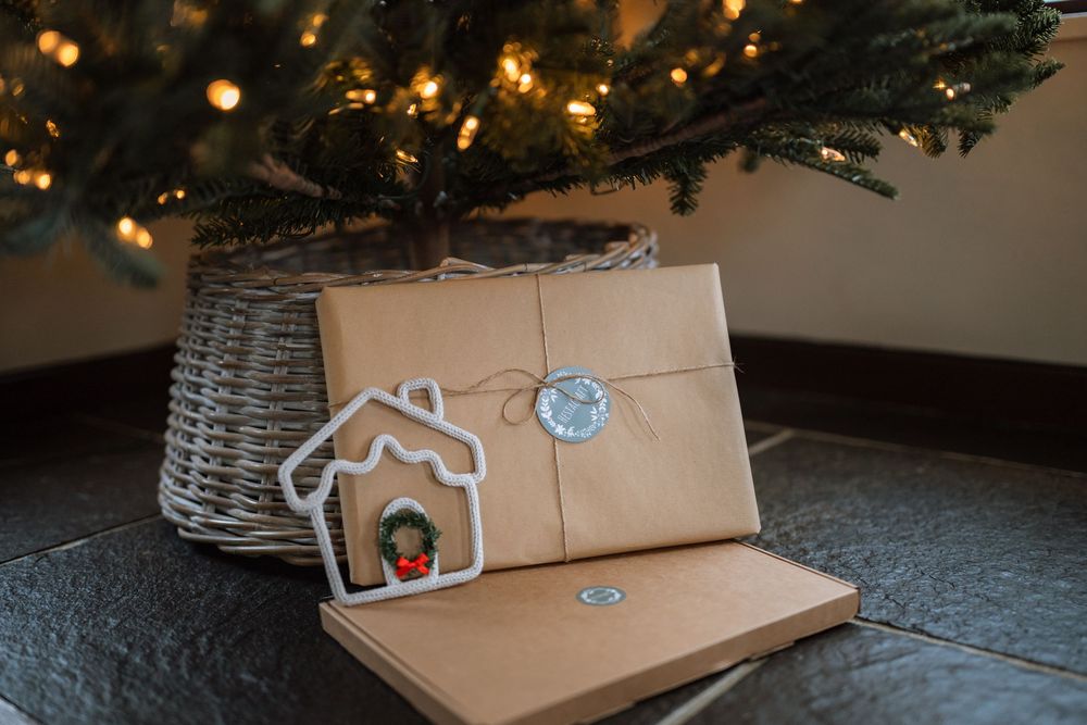 Brown paper packages with decorative cookie cutter ornaments displayed on a dark surface.