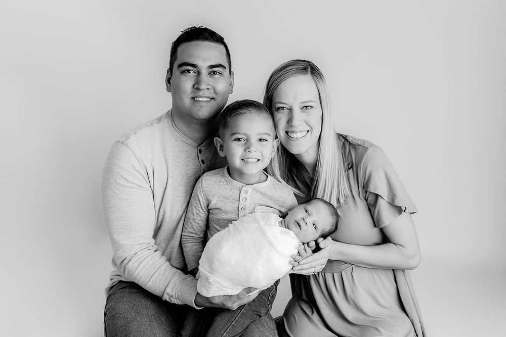 Black and white family portrait with parents and two children including a newborn baby.
