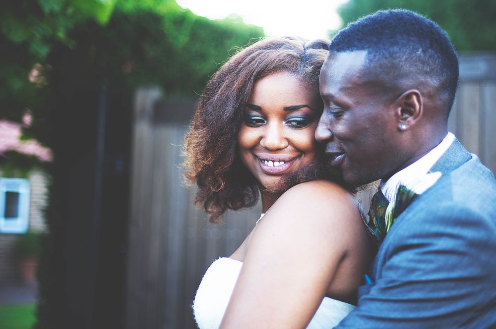 A joyful bride and groom share a romantic embrace outdoors on their wedding day, dressed in elegant attire. At Oaks farm wedding venue.
